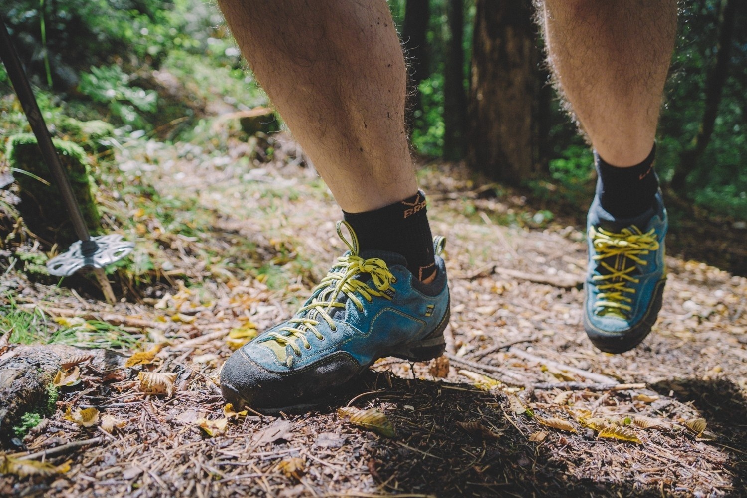 Oseba v modrih nizkih pohodniških čevljih hodi navzgor po poti