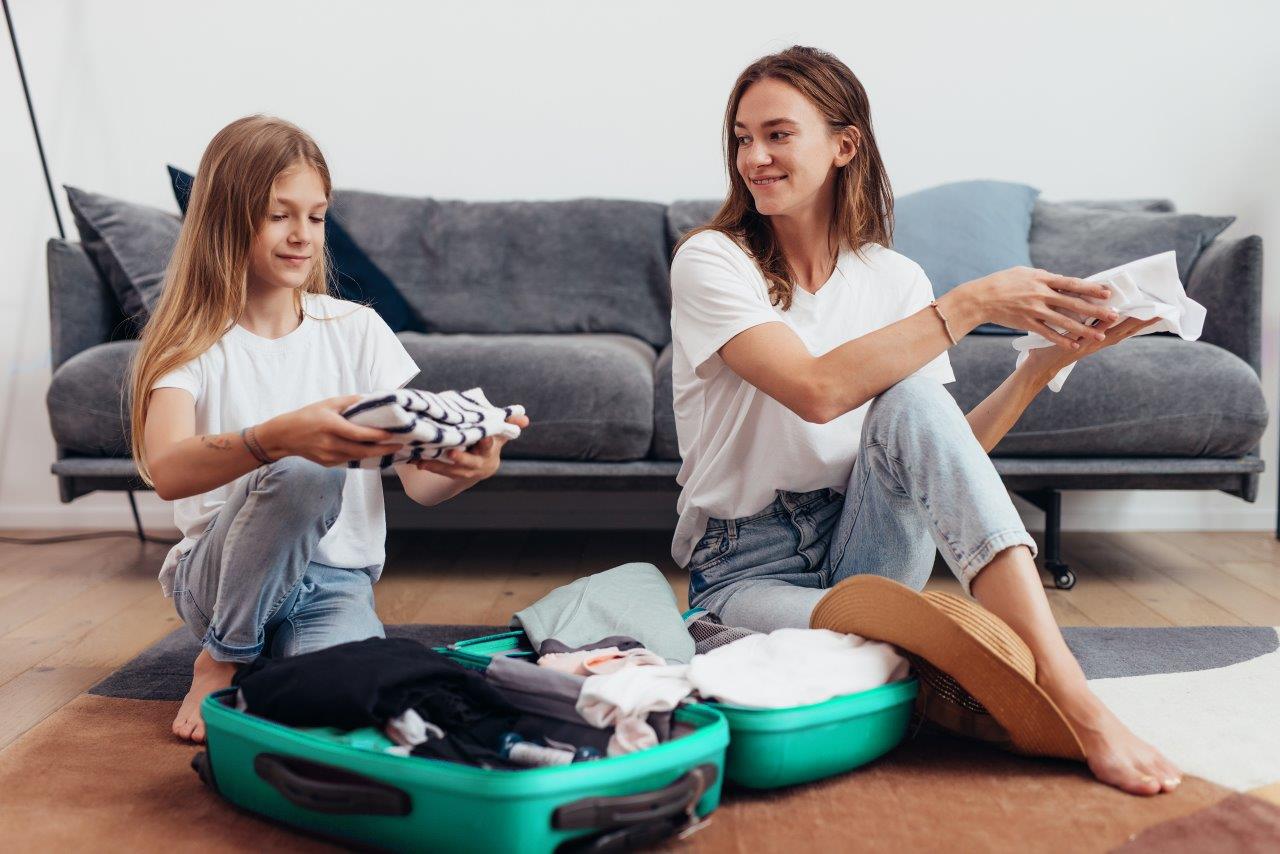 Ženska in dekle pakirata oblačila v potovalko