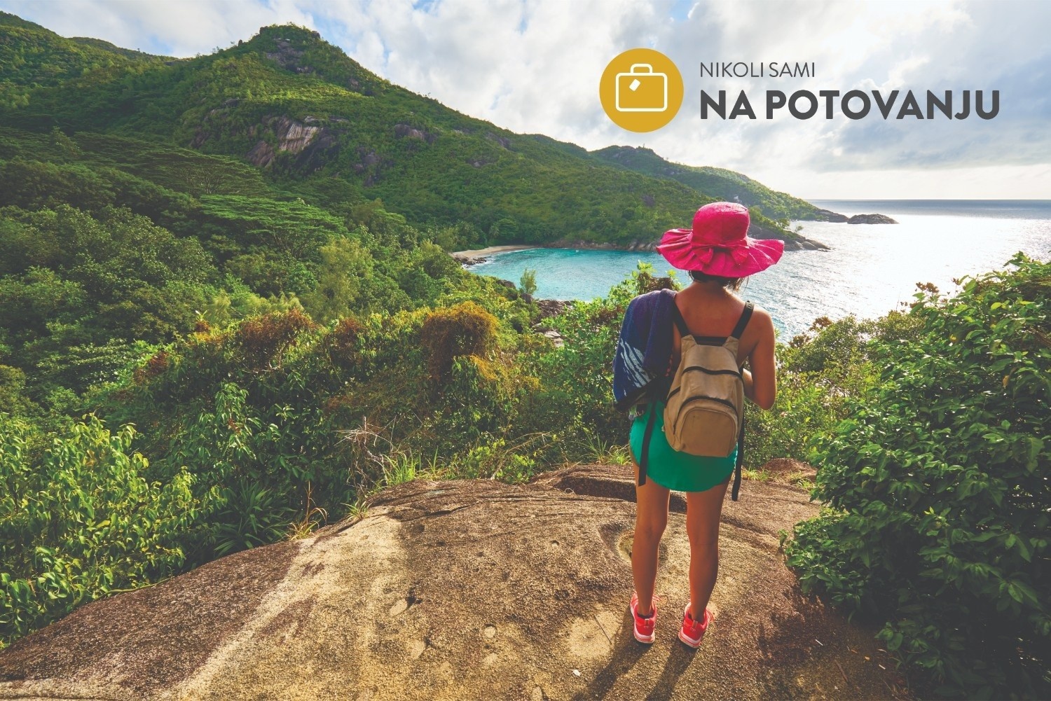 Poletno oblečena ženska stoji na hribu in gleda proti morju