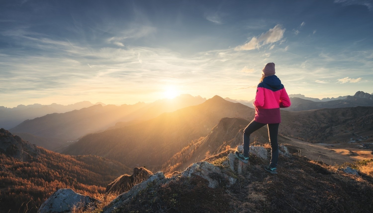 Pohodnica stoji na vrhu hriba in si ogleduje razgled