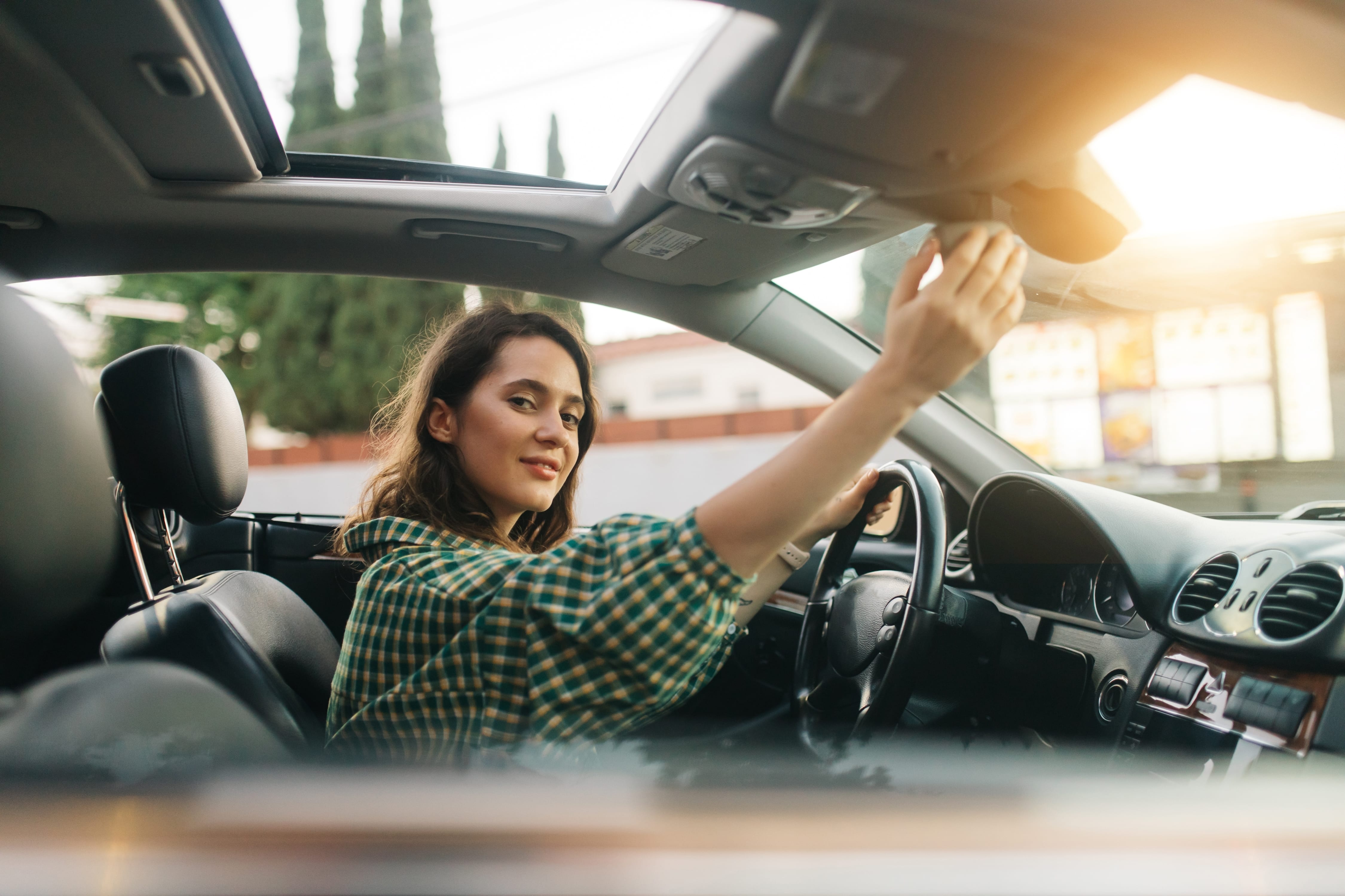 Ženska premika ogledala v avtu in se pripravlja na vožnjo