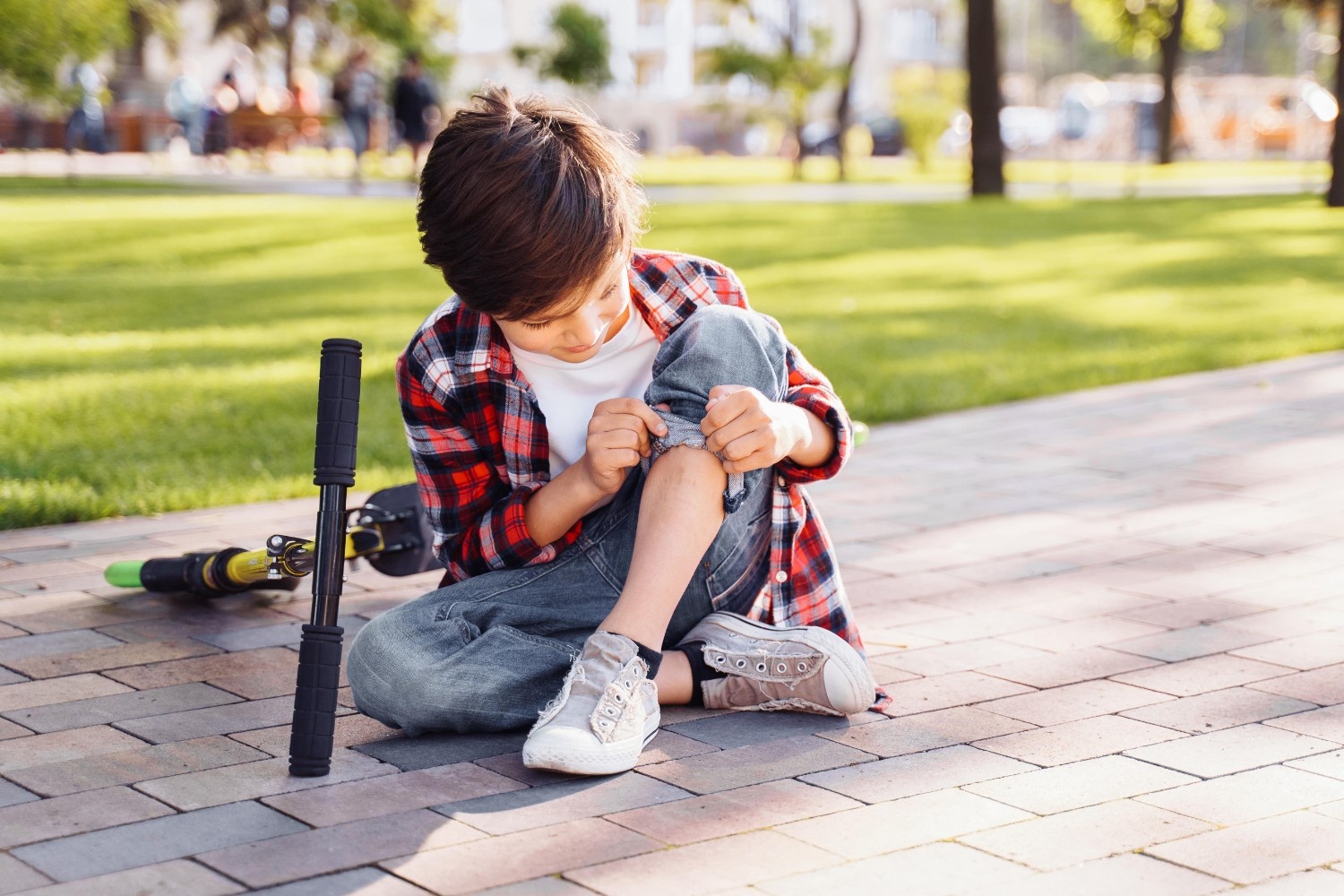 Fantek sedi na tleh in gleda prasko na nogi, za njim je skiro