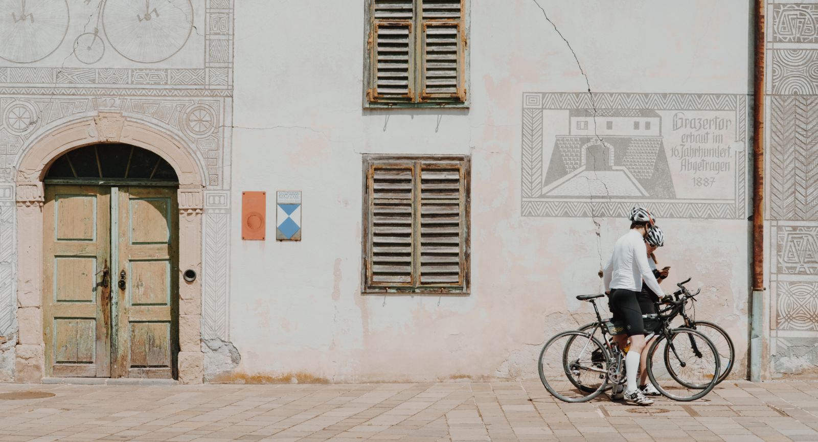 Dva kolesarja stojita sredi mesta, gledata v telefon in načrtujeta naprej pot